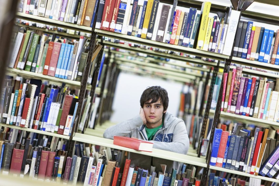 Image of male student in a library reading